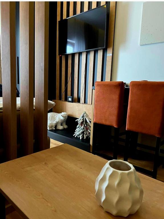 a table with a vase on top of a table with a television at N-LUX 66 MILMARI kopaonik in Kopaonik
