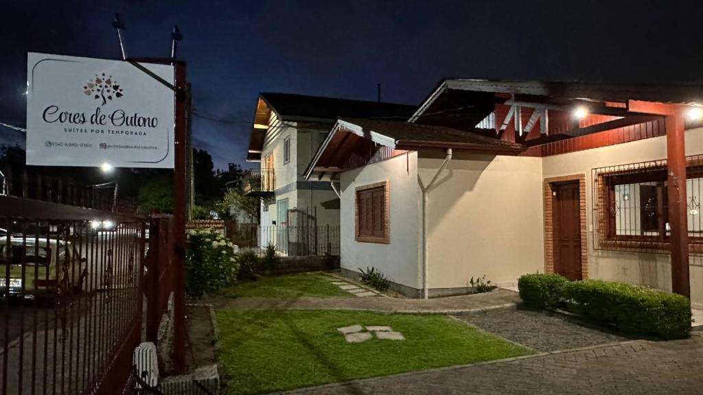 een huis met 's nachts een bord ervoor bij Cores De Outono Suítes in Canela