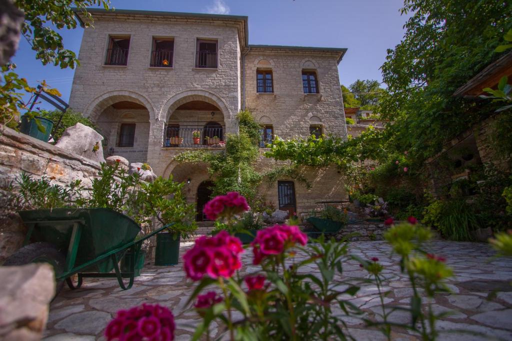 un grand bâtiment en pierre avec des fleurs devant lui dans l'établissement Casa Calda, à Syrrako