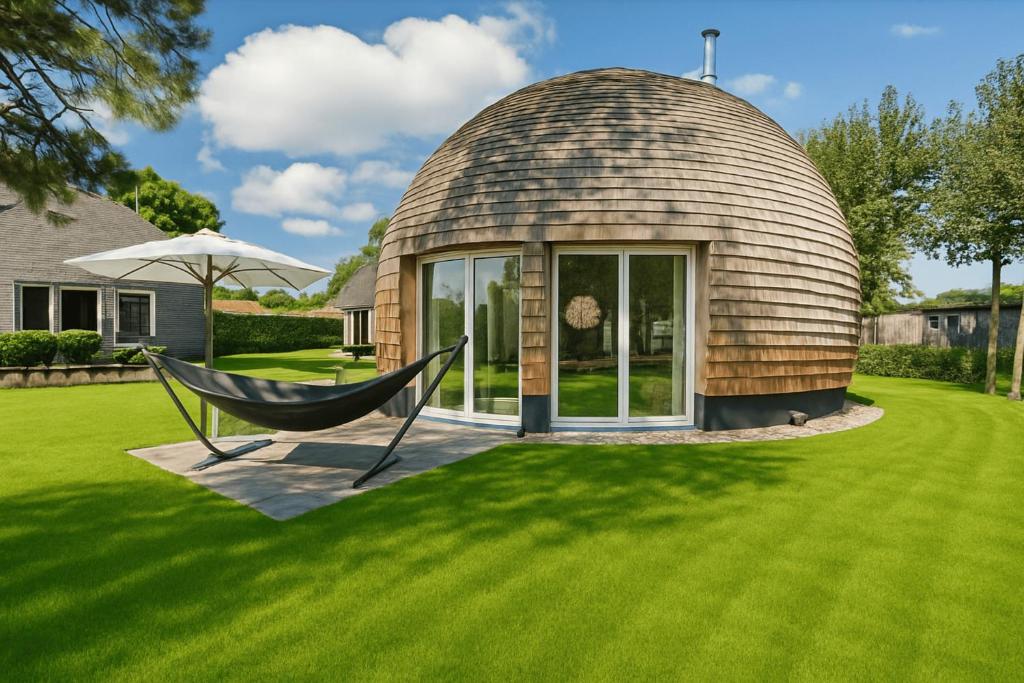 ein Kuppelhaus mit einer Hängematte im Garten in der Unterkunft Nordkugel - Rundes Wohnglück am Tollensesee in Wustrow