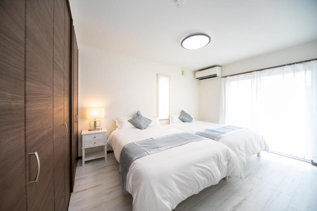 a white bedroom with two beds and a window at Awaji Riverside Terrace in Shizuki - Vacation STAY 81986v in Shizuki