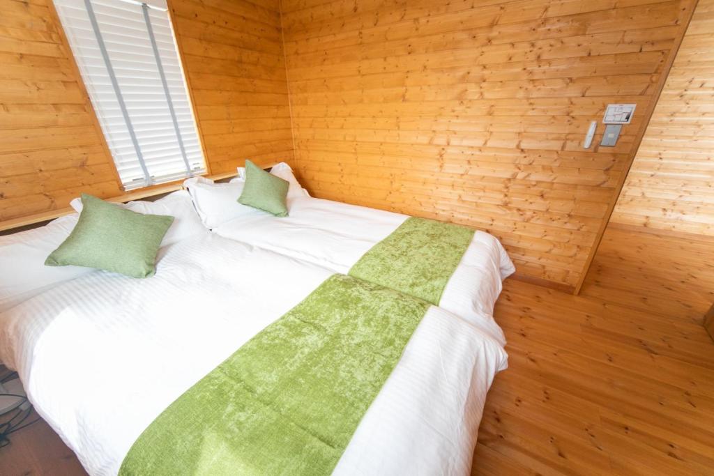 a bedroom with a large white bed with green pillows at Ａｗａｊｉ Ｓｅａｖｉｅｗ Ｒｅｓｏｒｔ ｉｎ Ｎｏｊｉｍａ - Vacation STAY 81998v in Kusumoto
