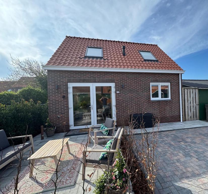 a brick house with a patio with chairs at Casa Del Faro in Westkapelle