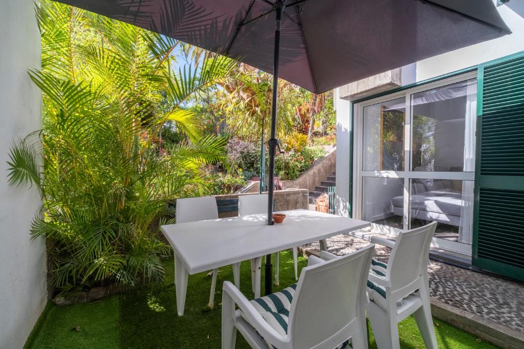 ein Tisch und Stühle mit einem Sonnenschirm auf einer Terrasse in der Unterkunft Lido Oasis Funchal in Funchal