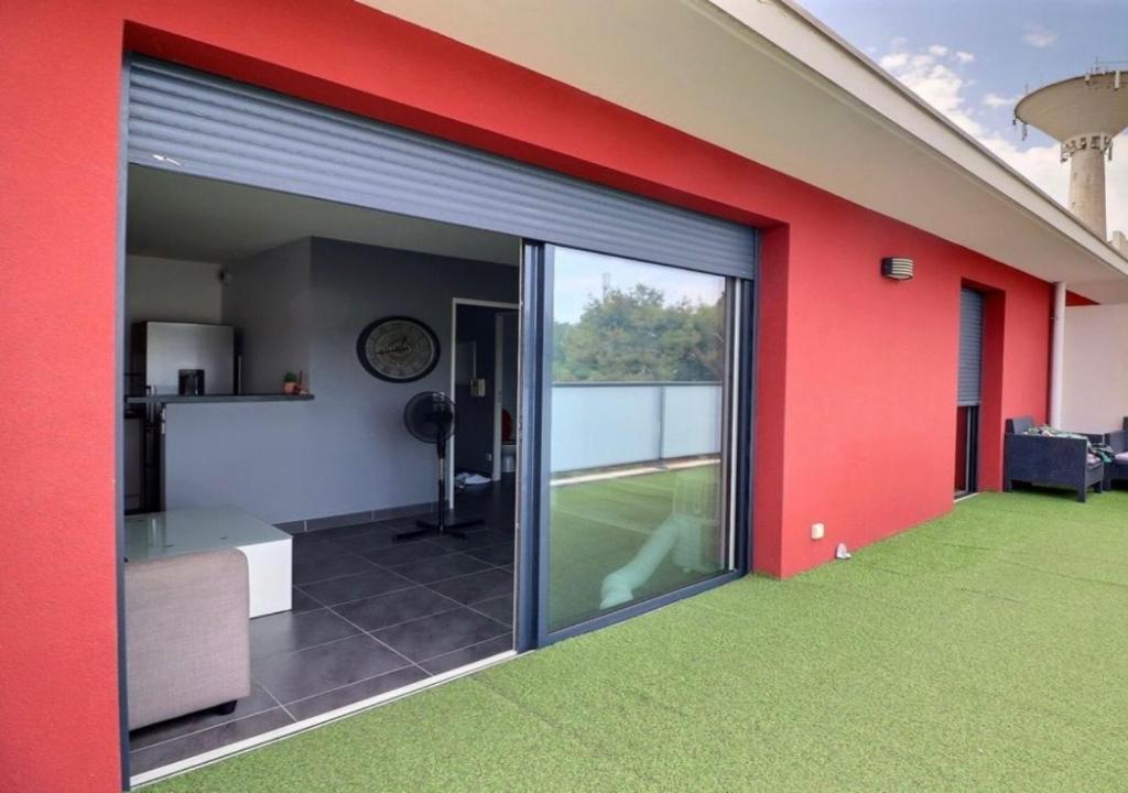 ein Zimmer mit einer roten Wand und einer großen Glasschiebetür in der Unterkunft Appartement Cosy in Le Crès