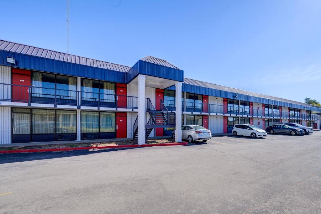 a large building with cars parked in a parking lot at Capital O Travelers Inn Lawton Fort Sill in Lawton