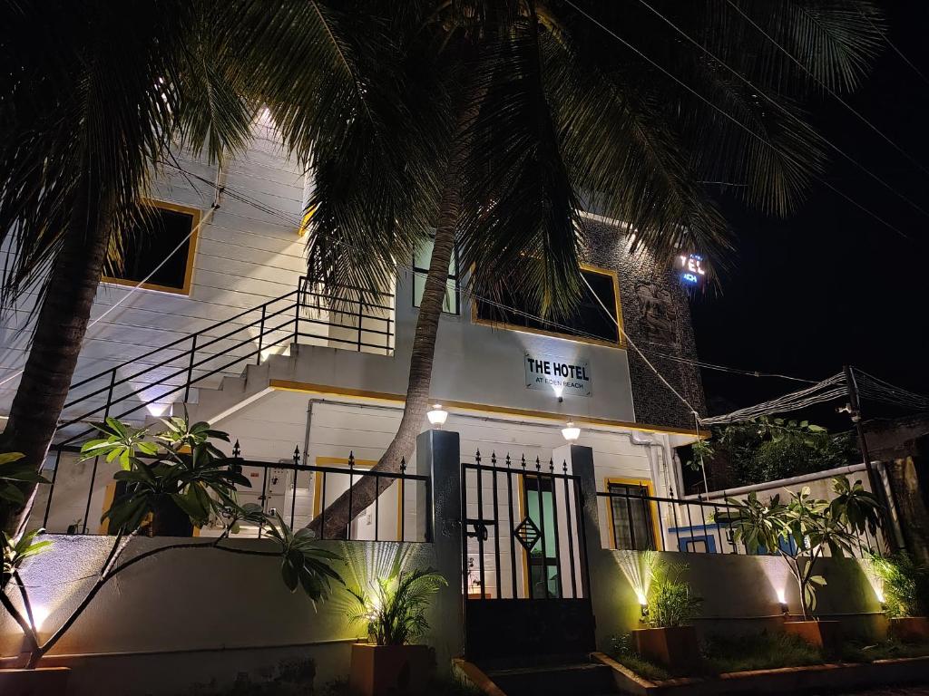 a white house with a palm tree in front of it at The Hotel Eden Beach in Puducherry