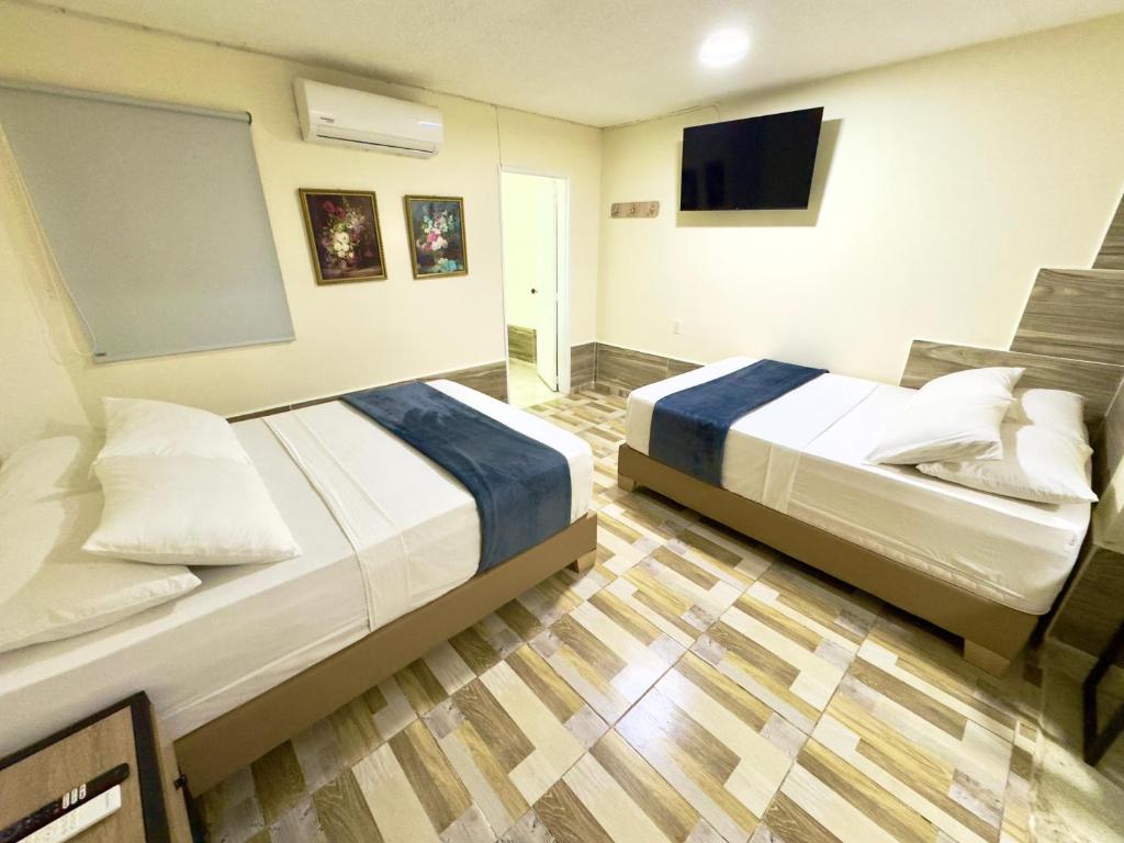 a hotel room with two beds and a flat screen tv at Hotel Estadio 80 in Medellín