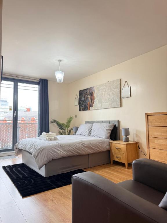 ein Schlafzimmer mit einem großen Bett und einer Couch in der Unterkunft Nexus - Top Floor City Views, Balcony & Parking in Birmingham