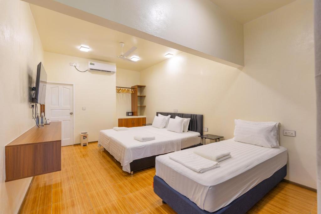 une chambre d'hôtel avec deux lits et une télévision dans l'établissement Dacha Thoddoo White Sand, à Thoddoo