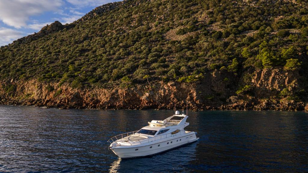 una barca bianca in acqua accanto a una montagna di DS MAI Sailing ad Atene