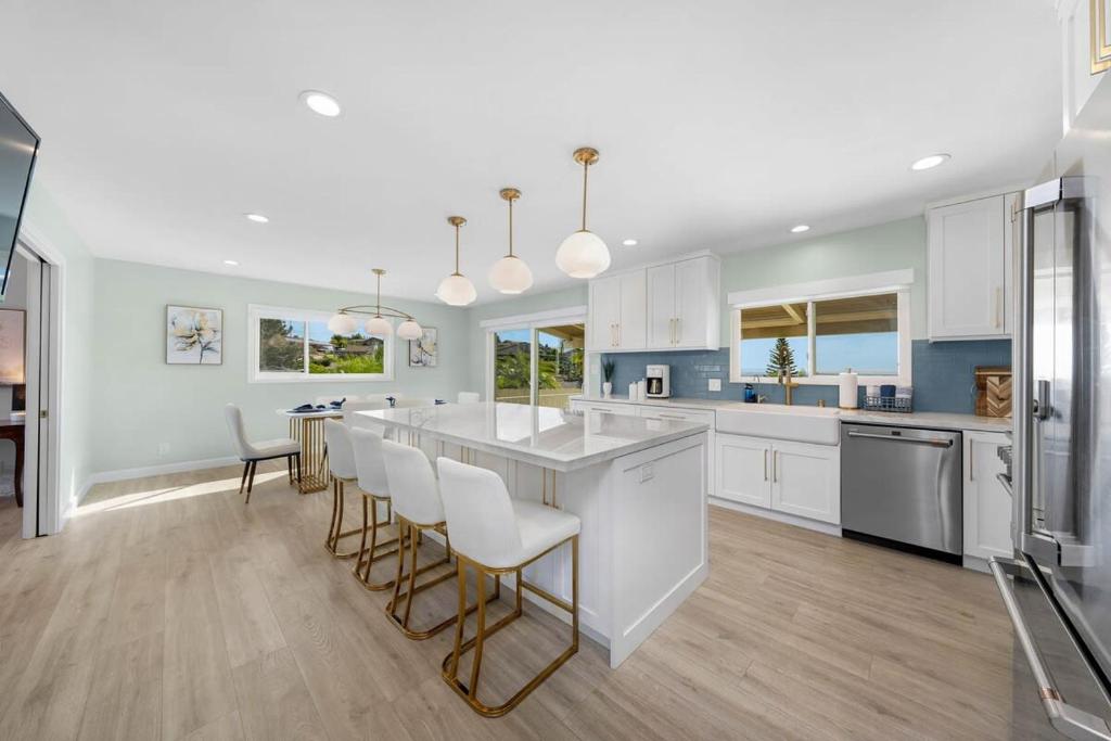 a kitchen with white cabinets and a large island with bar chairs at Family Hilltop luxe retreat with breathtaking views in La Mesa