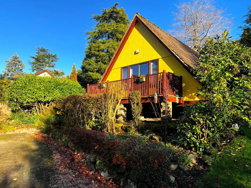 a small yellow house with a red balcony at Ericht Holiday Lodges in Blairgowrie