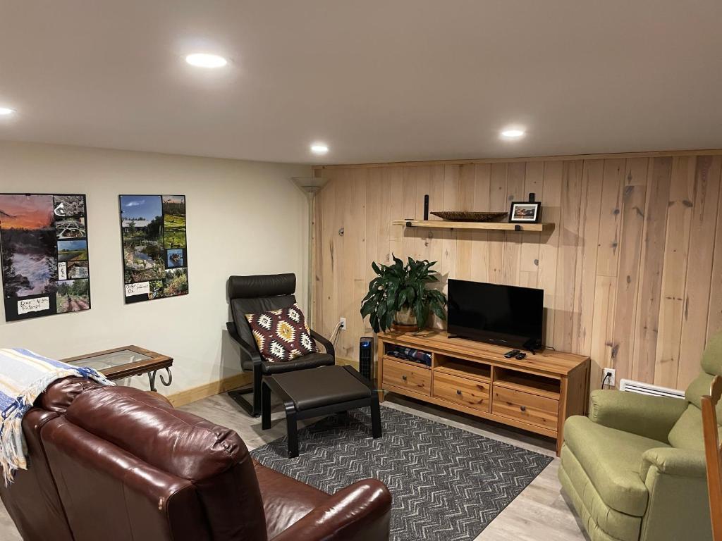 een woonkamer met een bank en een televisie bij La forêt nourricière in La Tuque