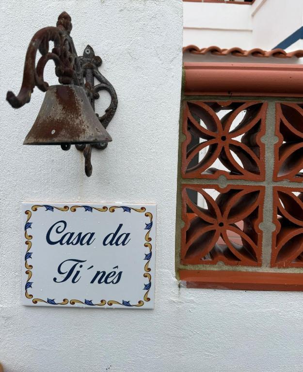 a bell hanging on a wall with a sign at Casa da Ti'nês in Bombarral