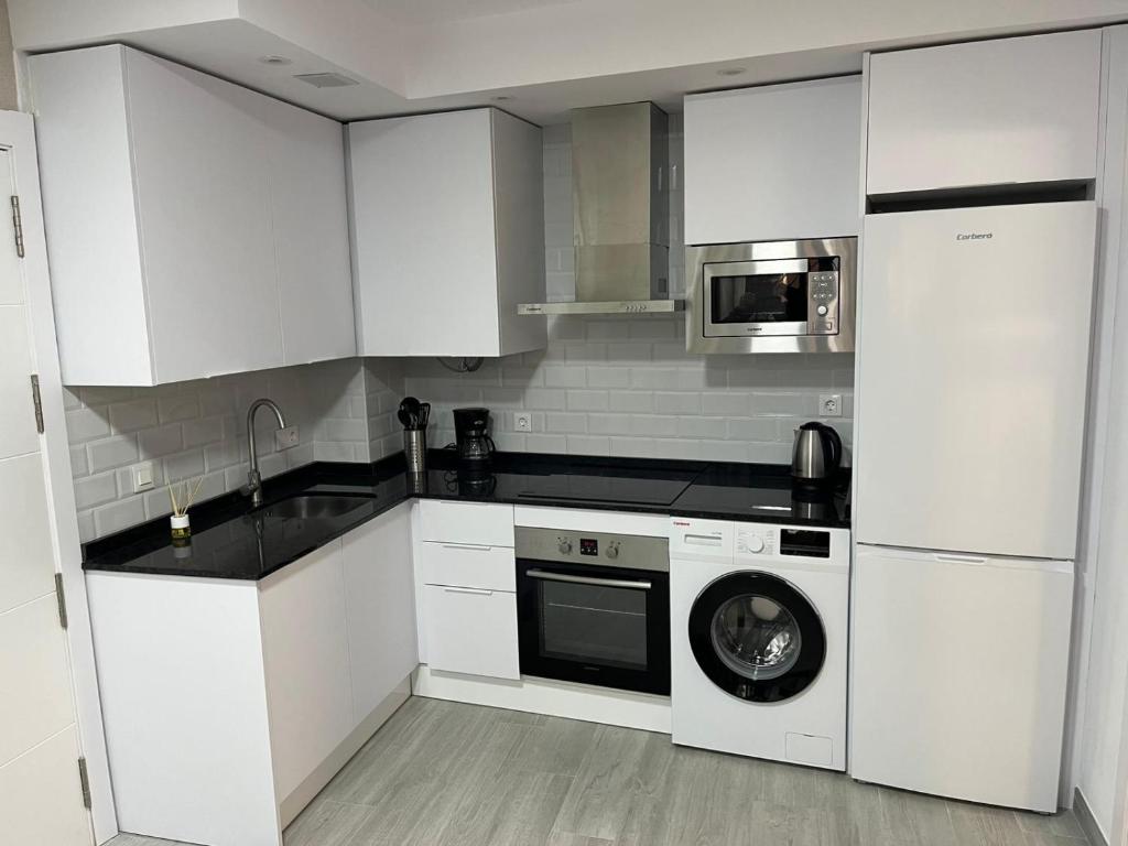 Una cocina con gabinetes blancos y lavadora. en Olas del Sur Apartment, en La Cala de Mijas