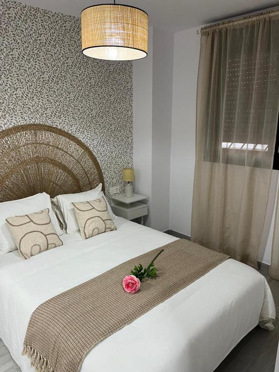 a bedroom with a white bed with a flower on it at Olas del Sur Apartment in La Cala de Mijas