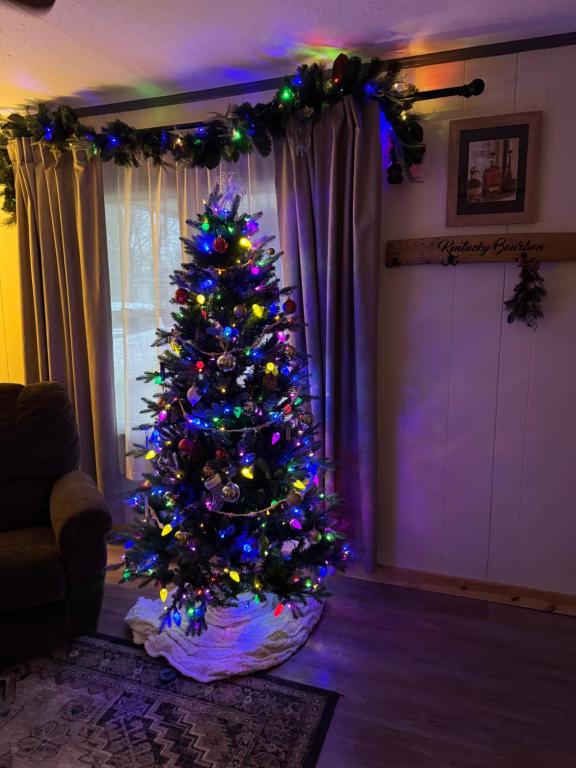 einen Weihnachtsbaum in einem Wohnzimmer mit blauen Lichtern in der Unterkunft Relax & Unwind Cozy Farmhouse Near Natural Bridge State Park in Stanton