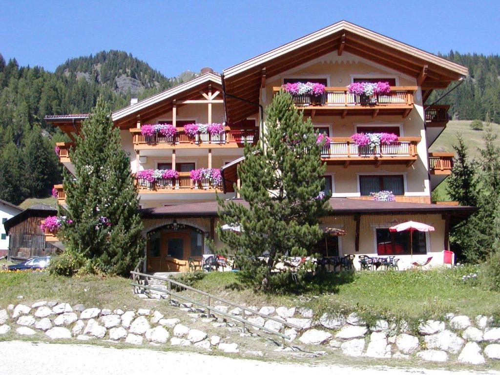 un gran edificio de apartamentos con flores en los balcones en Hotel Dolomites Inn, en Canazei