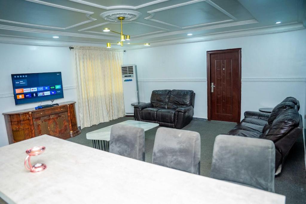 a room with chairs and a table and a tv at Spacious 4-Bedroom Apartment for families & groups in Benin City