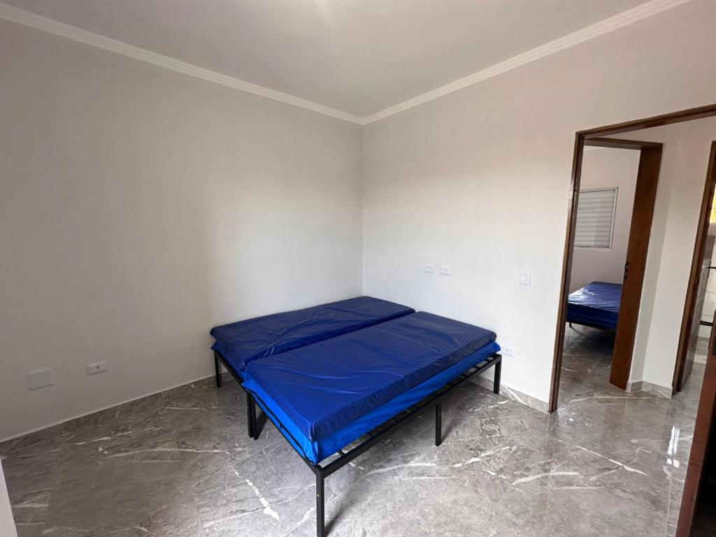 um pequeno quarto com uma cama azul e um espelho em Casa de condomínio com piscina e churrasqueira em São Paulo