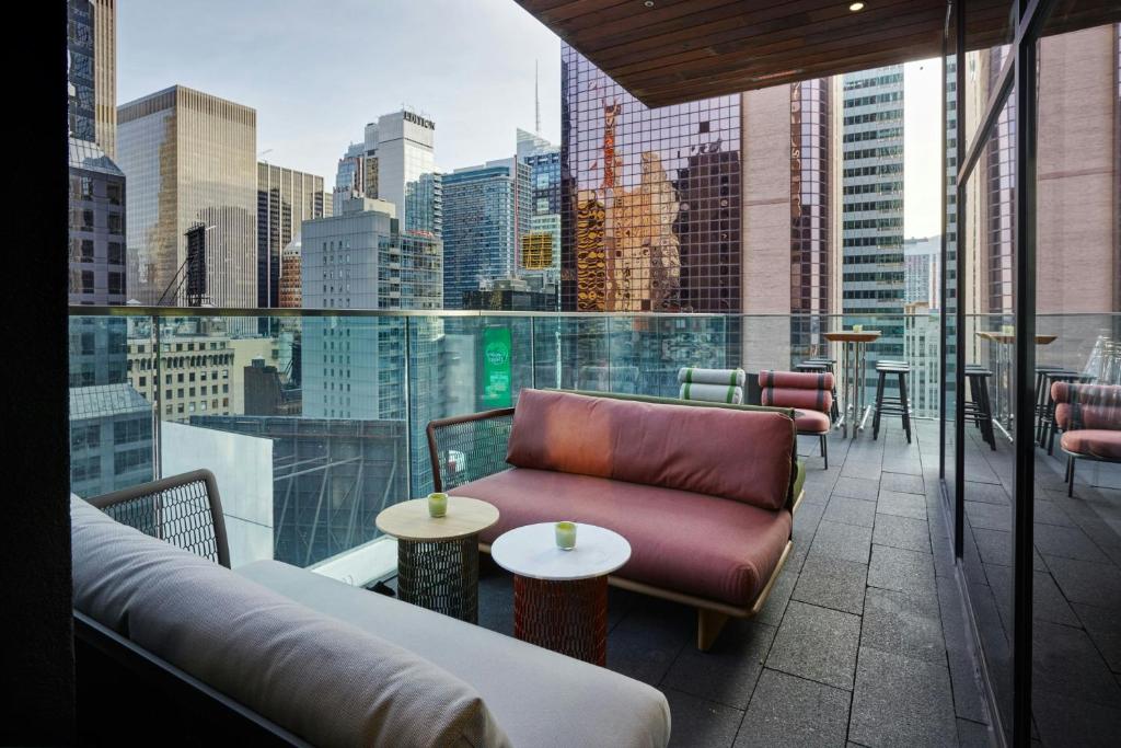 a balcony with a couch and tables and a city skyline at citizenM New York Times Square in New York