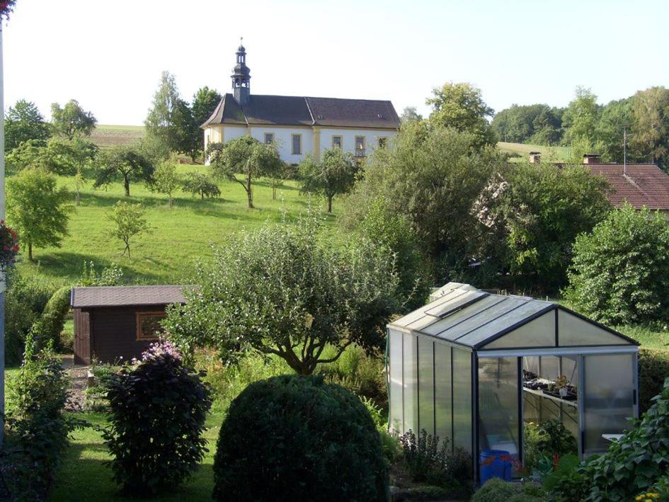 ein Gewächshaus in einem Garten mit einem Haus im Hintergrund in der Unterkunft Ruhige Ferienwohnung mit Garten und Blick zur Wallfahrtskirche in Ebensfeld