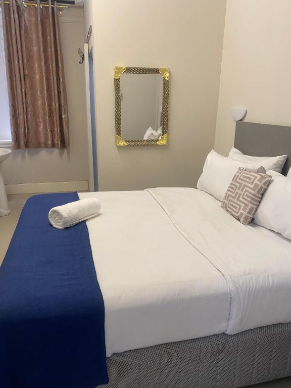 a bedroom with a large white bed with a mirror at JH Guest house in Durban