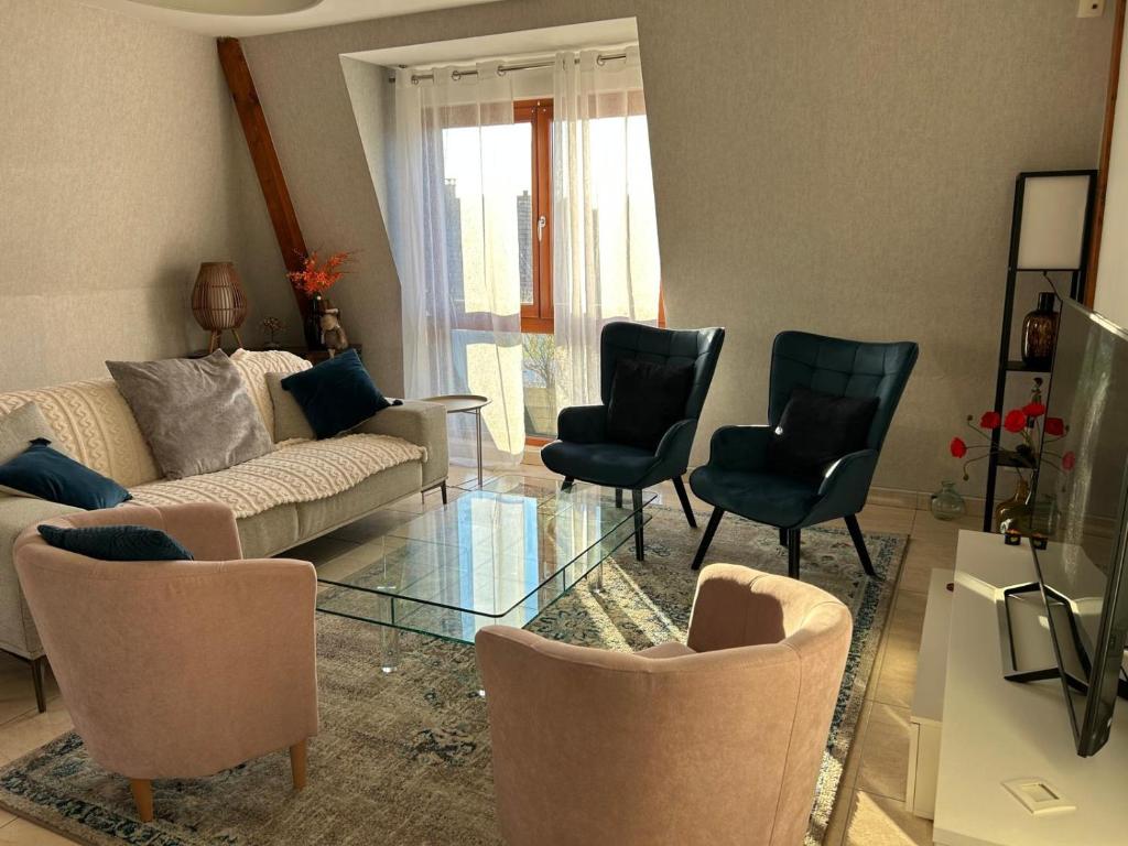 ein Wohnzimmer mit Couch und Stühlen in der Unterkunft Les pervenches in Illkirch-Graffenstaden