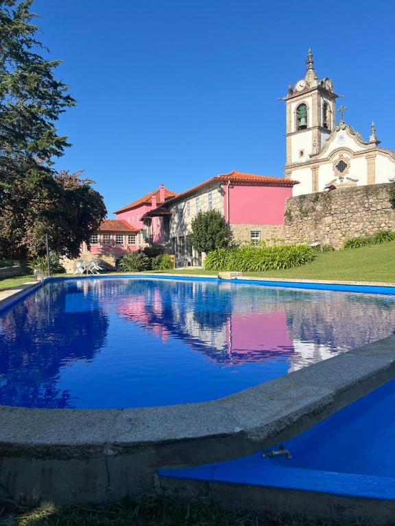 a church and a swimming pool in front of a church at Casa dos Assentos in Quintiães