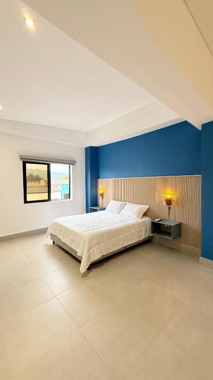 ein Schlafzimmer mit einem großen Bett und einer blauen Wand in der Unterkunft Hotel Gallery Boutique in Pereira