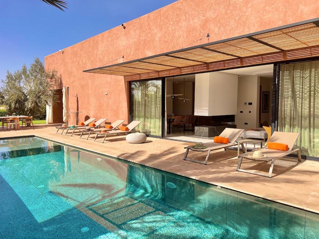 a swimming pool with chairs and a house at Villa AYA - Moderne & Chic in Sraghna