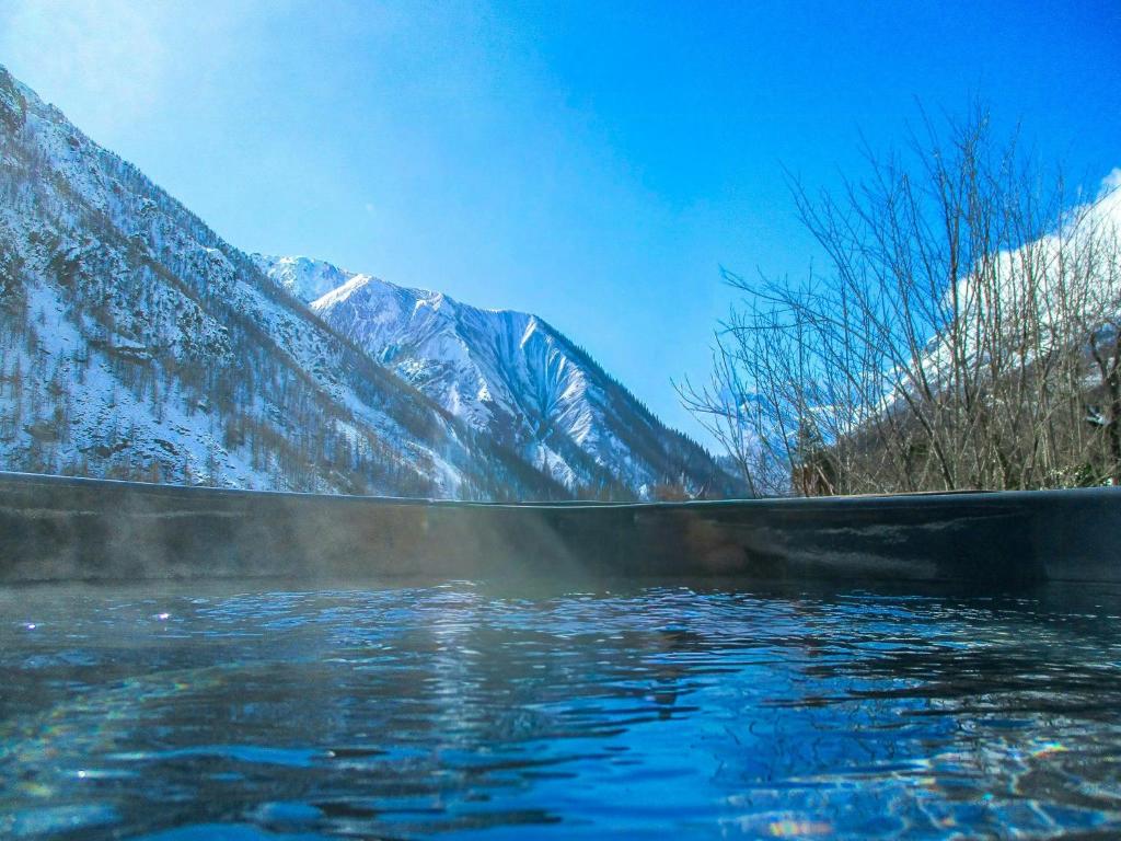 ein Wasserkörper mit verschneiten Bergen im Hintergrund in der Unterkunft Stone Mountain Cabin Overlooking Ala Valley in Alo di Stura