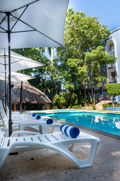 a group of chairs and an umbrella next to a pool at Hotel Maya Palenque in Palenque