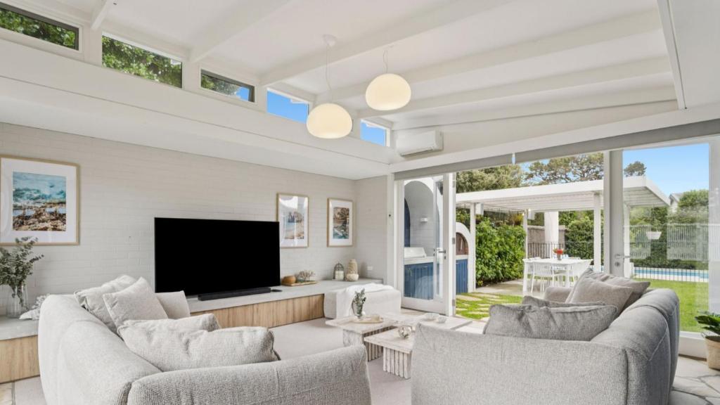 een woonkamer met witte meubels en een flatscreen-tv bij La Plage Portsea in Portsea