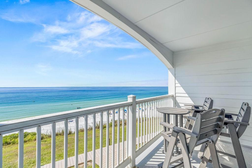 eine Veranda mit zwei Stühlen und einem Tisch und dem Meer in der Unterkunft Blue Tide 6B in Inlet Beach