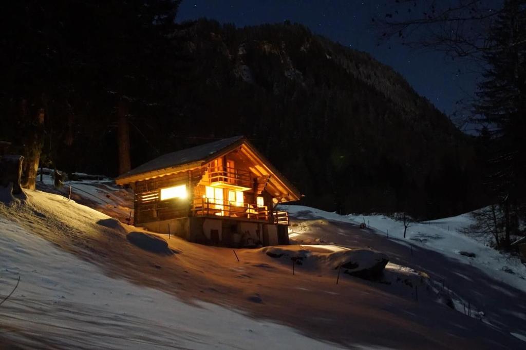 eine Blockhütte im Schnee bei Nacht in der Unterkunft Wollhaus Oberzwirgi 6-Bettwohnung in Rohrmatten