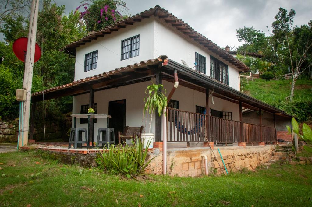 una casa blanca con un porche y un patio en Finca campestre San Juan, un paraíso en medio de la naturaleza, en San Gil