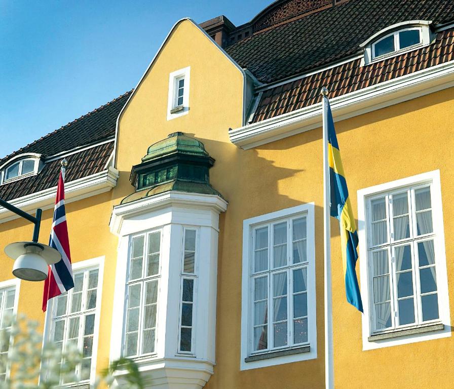 two flags on the side of a yellow building at Grand Hotel Alingsås in Alingsås