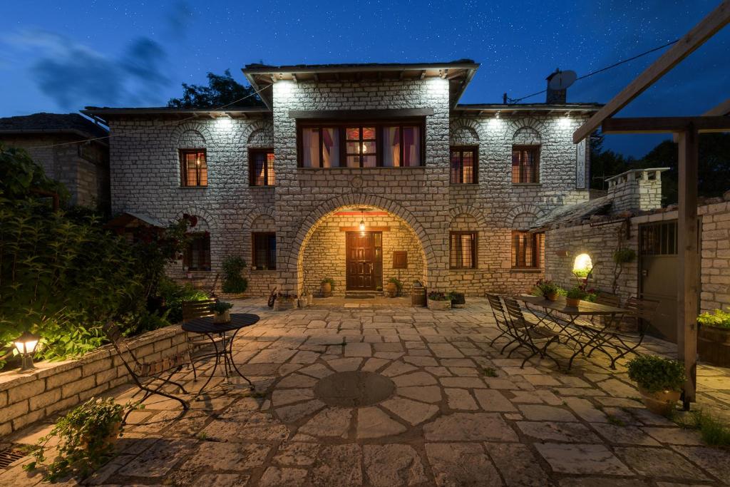 a stone house with a courtyard at night at Vikos Hotel in Monodendri