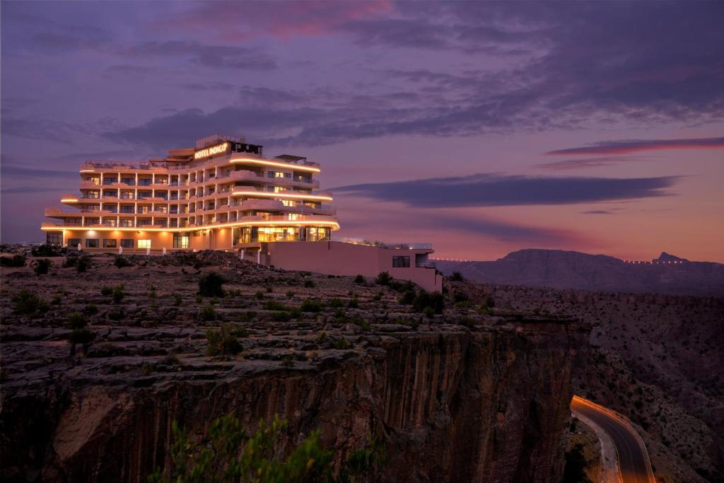 un bâtiment situé sur le côté d'une montagne la nuit dans l'établissement Hotel Indigo Jabal Akhdar Resort & Spa by IHG, à Al ‘Aqar
