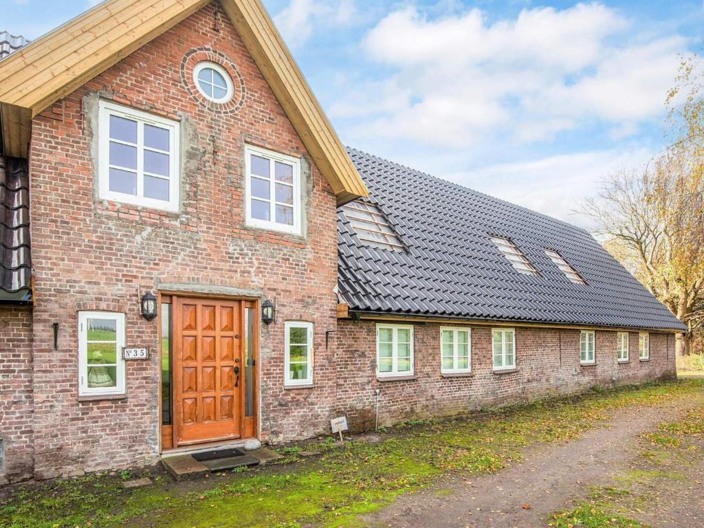 Emmerlev4 star holiday home in Højer的砖房,有棕色的门和车道
