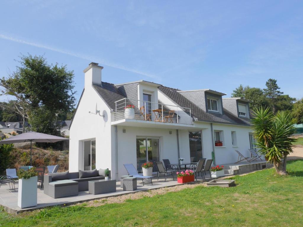 a white house with a patio and lawn at Holiday home with partial sea view, Douarnenez in Tréboul