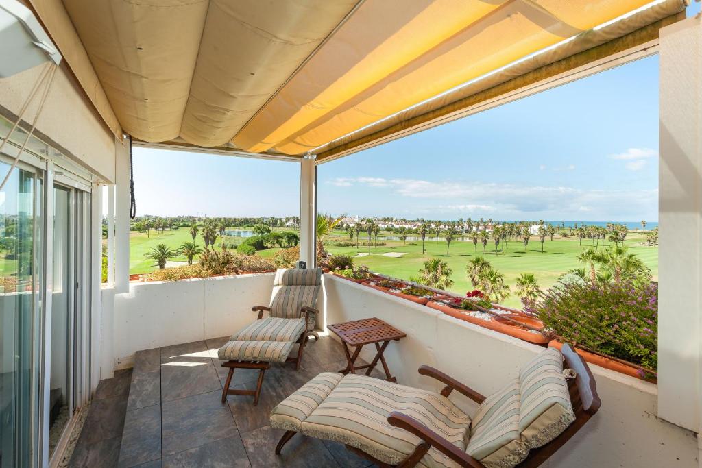 balcón con sillas y vistas al campo de golf en artQhost Costa Ballena Penthouse Ocean and Golf views & Free Parking, en Costa Ballena