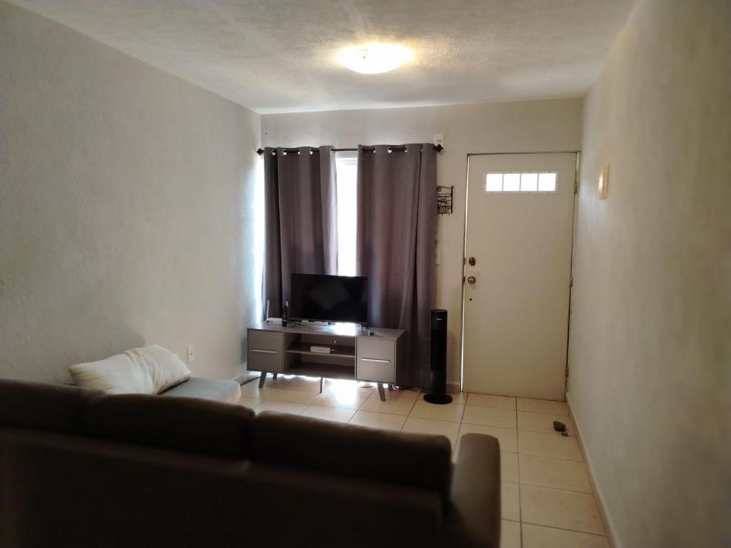 Una sala de estar con un sofá y un televisor. en Bonaterra, en El Jobo