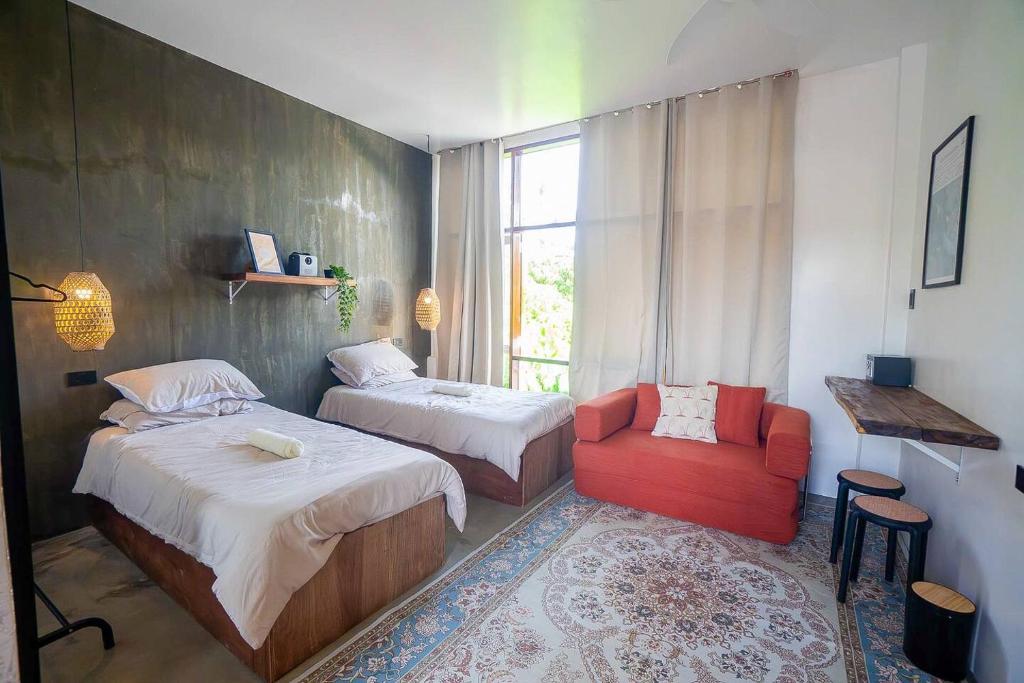 1 Schlafzimmer mit 2 Betten und einem roten Stuhl in der Unterkunft CIELO Siargao in General Luna