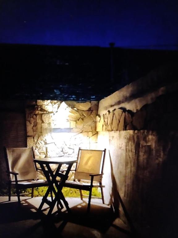 a table and chairs in front of a stone wall at night at Lajas del Parque in Tandil