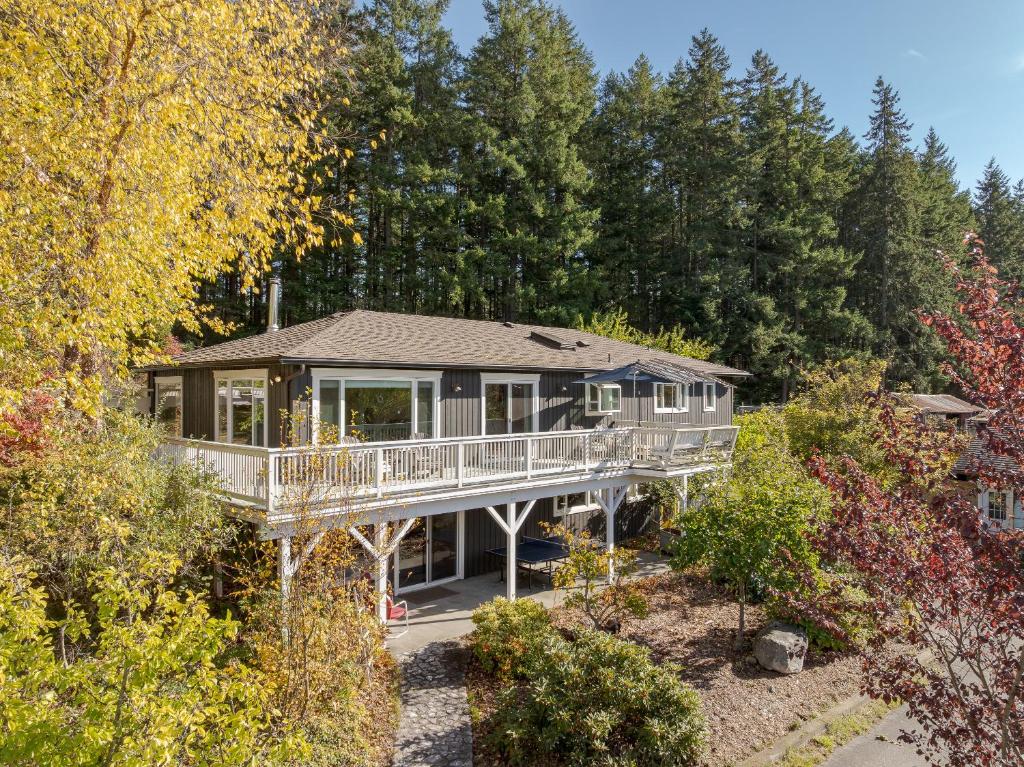 ein Haus mit umlaufender Terrasse inmitten der Bäume in der Unterkunft Hot Tub & Pizza Oven Spacious family farm house in Dolphin