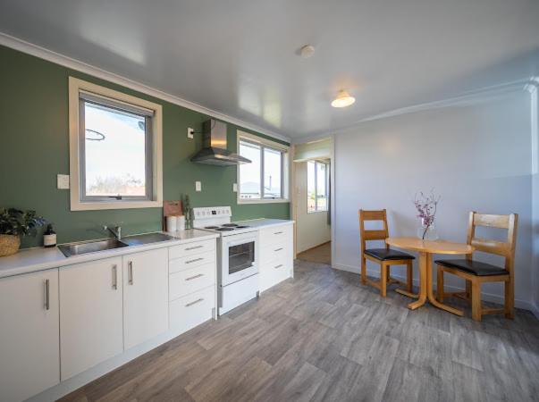 eine Küche mit einem Tisch und einem Tisch und Stühlen in der Unterkunft Te Anau Holiday House in Te Anau
