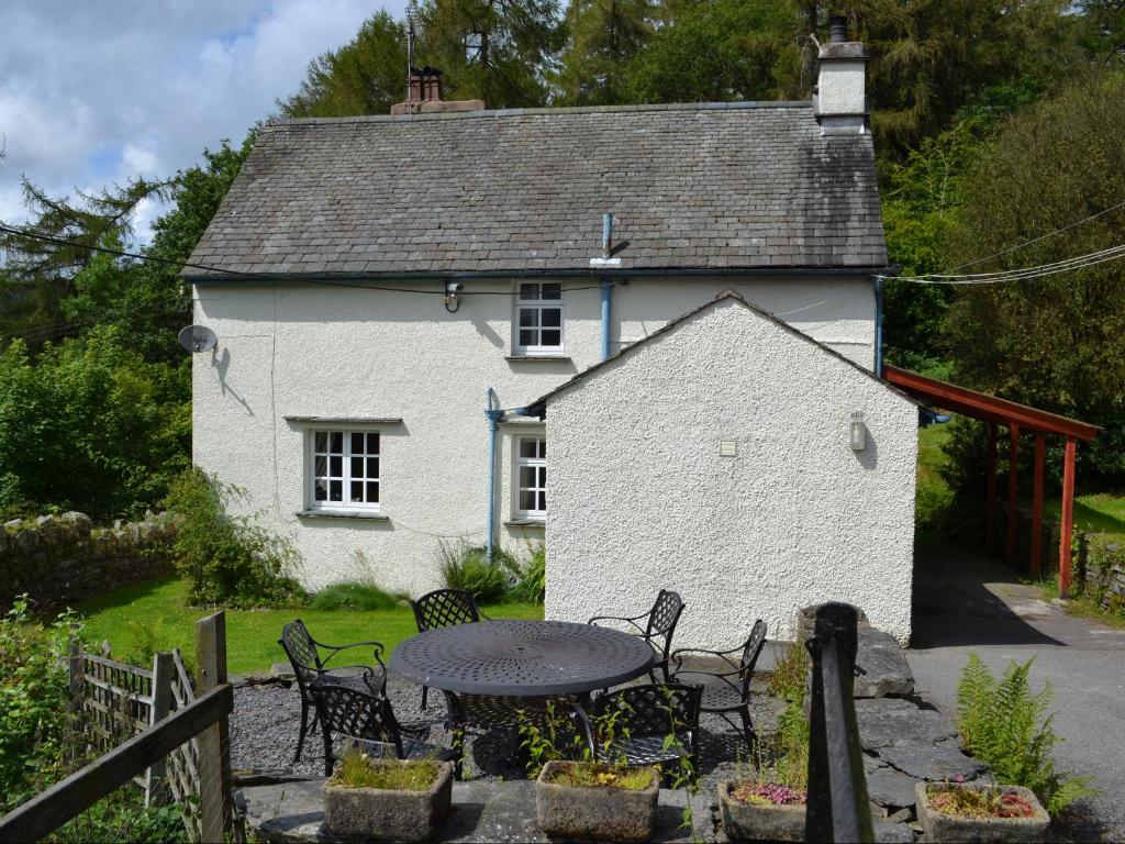 a table and chairs in front of a white house at Breasty Haw in Grizedale